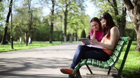 Female friends with tablet computer in the park, dolly shot
