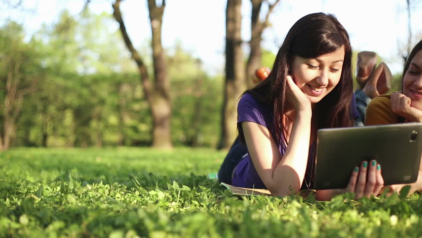 Happy female friends with tablet computer in the park, dolly shot

