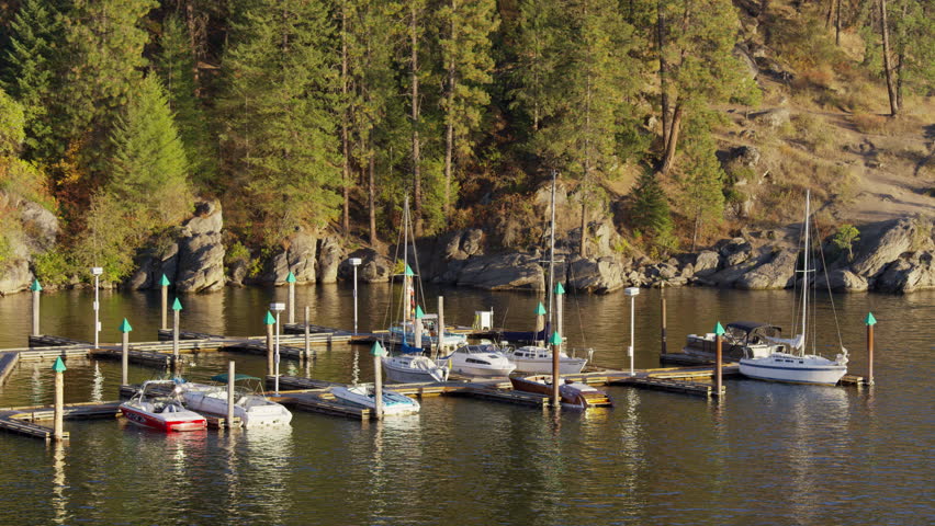 Wide shot of sailboats at dock on shimmering lake / Coeur d