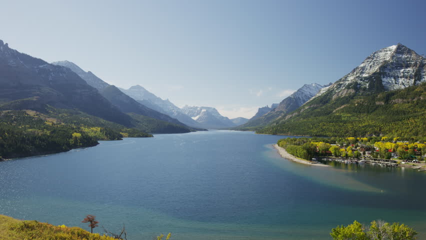 Wide panning shot of river bending near mountains / Waterton Lake, Alberta, Canada
