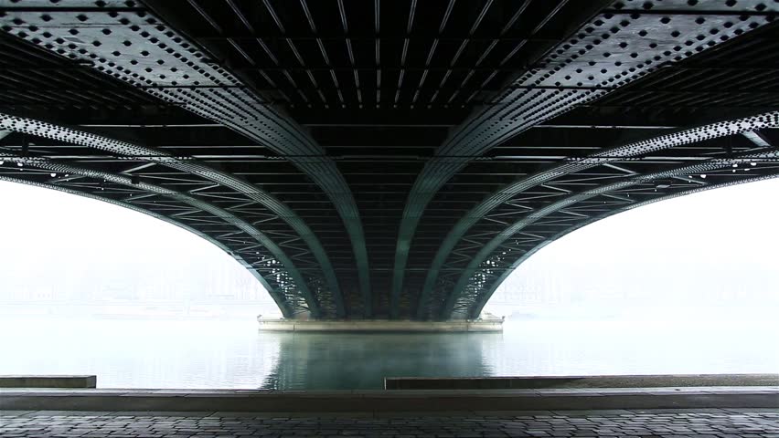 Man walking under a old bridge in Lyon, France, on a foggy, autumn morning.