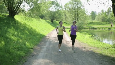 Two young girls jogging in the park, slow motion