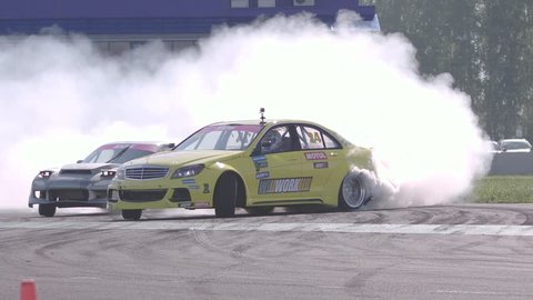 Ryazan, Russia - September 1, 2016 : Slow motion shot of two cars drifting with lots of smoke during drift competition in Ryazan, Russia on a sunny autumn day.