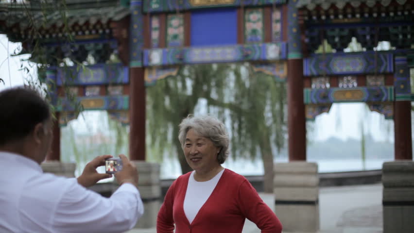 MS Mature man taking photo of elderly woman in front of traditional Chinese gate / Beijing, China