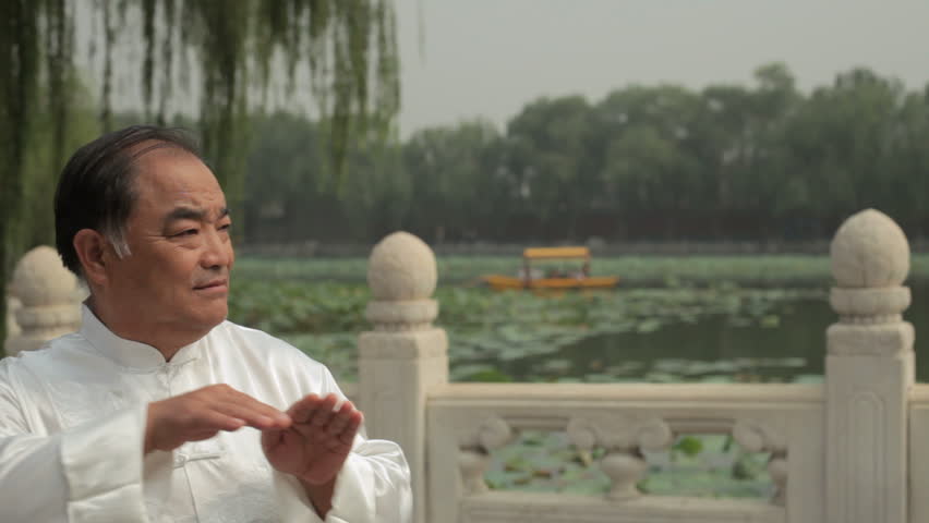 MS Mature man doing Tai Chi by lake /Beijing, China