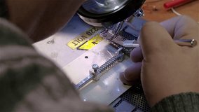 White man repairing broken smartphone in workshop. Preparing motherboard to replace chip