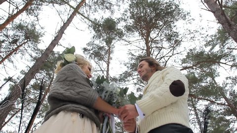 Wedding engagement ceremony of lovely young couple in winter pine forest
