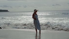 Young blonde woman in dress and hat on the beach, Bali