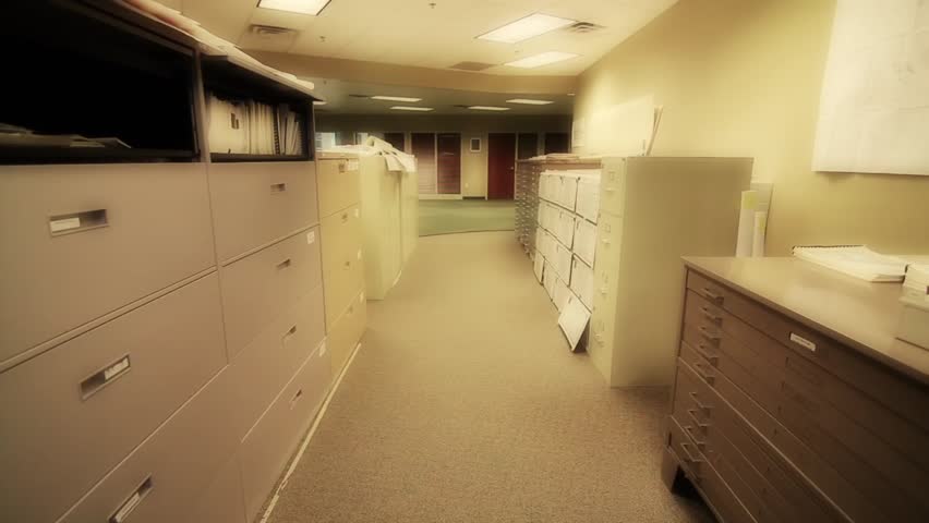 A man searches through large filing cabinets at his business