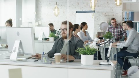 Weekday in a Busy Creative Bureau. Diverse Cast of People at Work. Office Workers Sit at Their Personal Computers. At the Big Table Have Planning Session.Shot on RED EPIC (uhd).