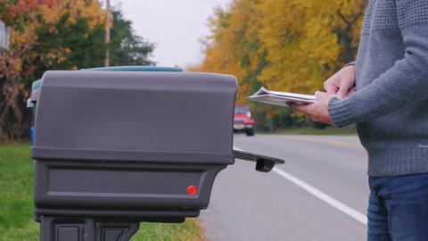 Unrecognizable man picks up the mail from the mailbox