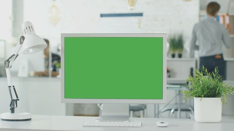 Close-up of a Green Screen on a Personal Computer. In Background Blurred and Brightly Lit Office where People go Through Office Routine. Shot on RED EPIC (uhd).