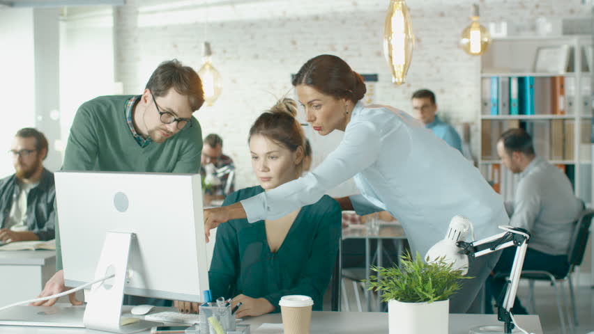 Young  Man and Two Women Stand before Computer Desk in a Creative Office. They Discuss Business Issues. Diverse People Working in Background.  Shot on RED EPIC (uhd). | Shutterstock HD Video #22522282