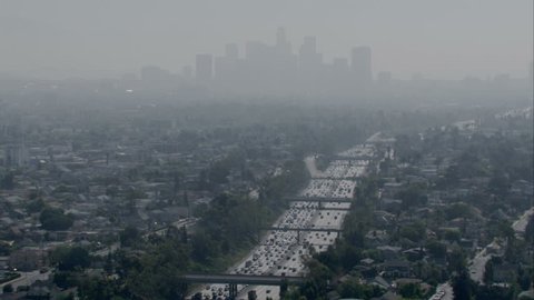 Aerial shot of a smoggy, overcast city with a major multi-lane freeway and skyline circa 2009