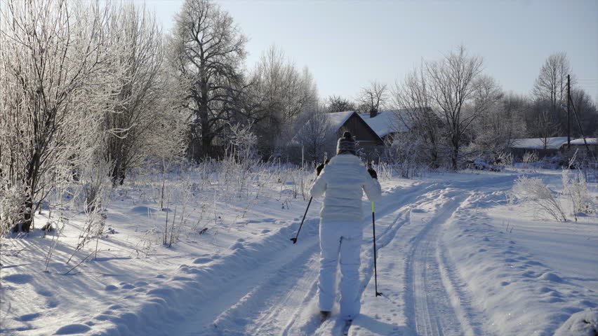 young girl skiing, village house background