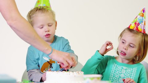 Little boy and girl licking candles at birthday party