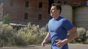 Medium slow motion tracking shot of man running in neighborhood / Antimony, Utah, United States