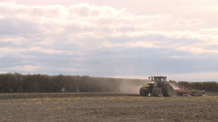 A large tractor and implement busy cultivating a field 