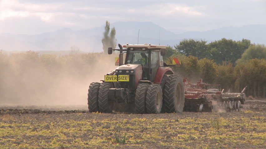 A large tractor busy cultivating a field 