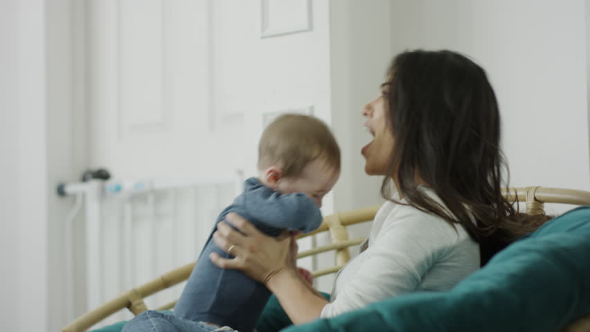 Medium shot of mother sitting in papasan chair lifting baby son / Provo, Utah, United States | Shutterstock HD Video #22539409