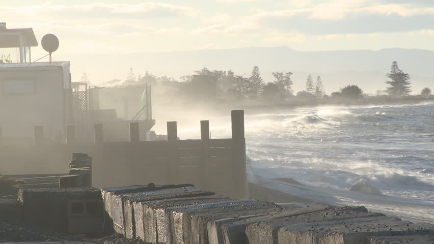 large waves crash into a coastal property