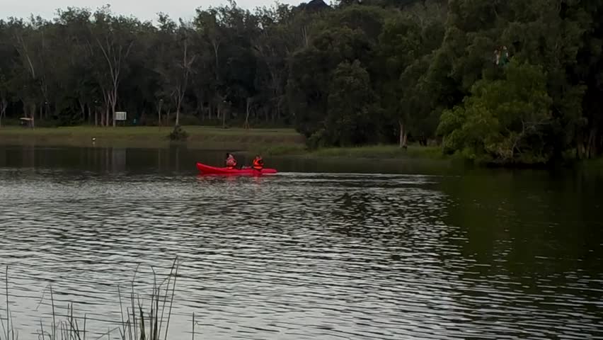 People playing red canoe on lake