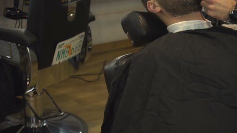 Barberman shaving beard of man