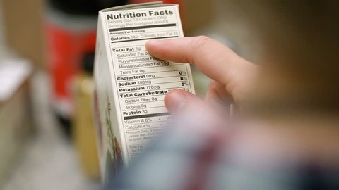 Female shopper reading nutritional information on a box of crackers. 