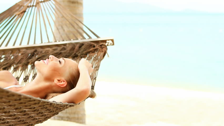 Cute woman lying on hammock on tropical beach
