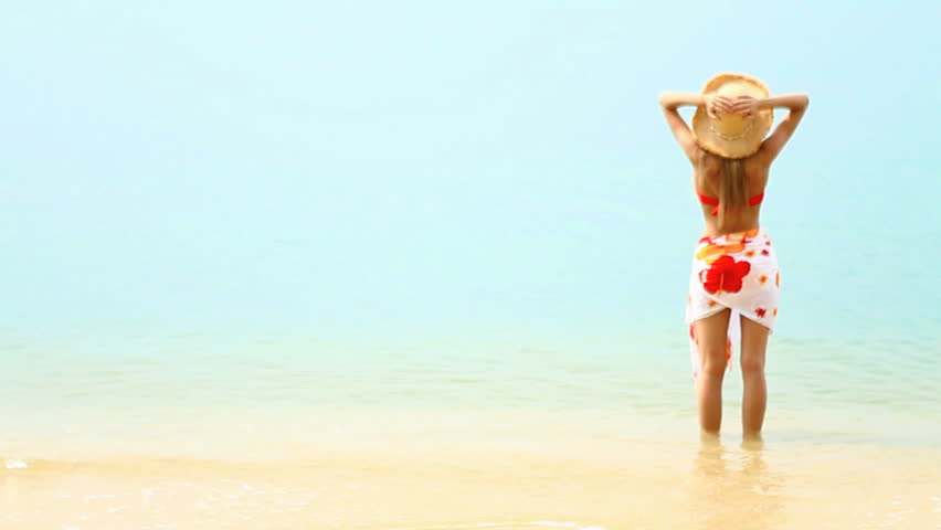 Woman enjoy warm tropical water at sandy exotic beach
