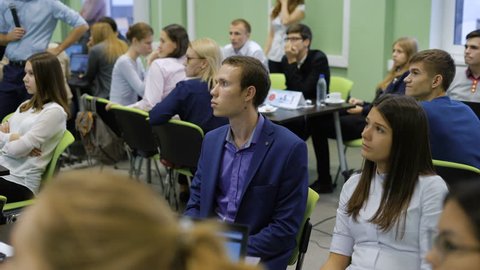 Young professionals in the audience of the institution in the training business. Teams taking part in the training carefully listening to the opponents.