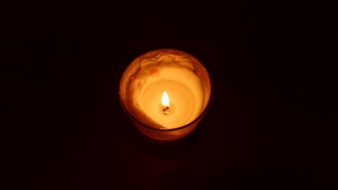Close-up of a match lighting a candle against a black background.