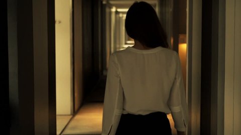 Elegant, young woman walking through hall in hotel
