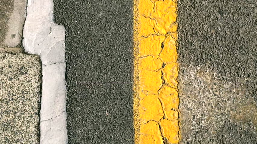Walk the line. A man walking along a yellow line.