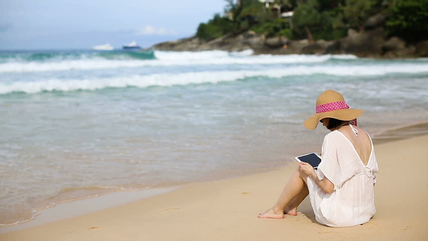 Young woman using a mobile phone on the beach. the mobile Internet in roaming. 4g, 5g, LTE concetp. 
