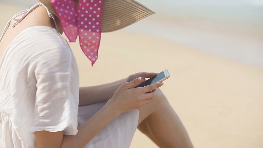 Young woman using a mobile phone on the beach. the mobile Internet in roaming. 4g, 5g, LTE concetp. 