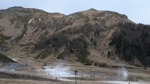 Snowmaking gun and chairlifts in the mountains. Puy de Sancy, France.
