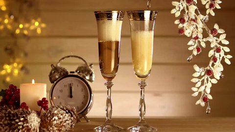 New Year and Christmas Celebration with Champagne.  Two glasses of champagne, candle and  clock.  Full HD 1080 video footage. Slow motion 240 fps.