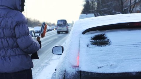 Woman cleaning Snow and Ice off her Car, selective focus