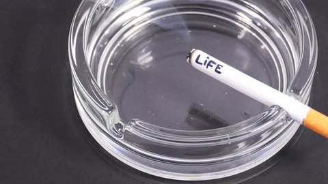 Close up cigarette with word 'life' in ashtray. 