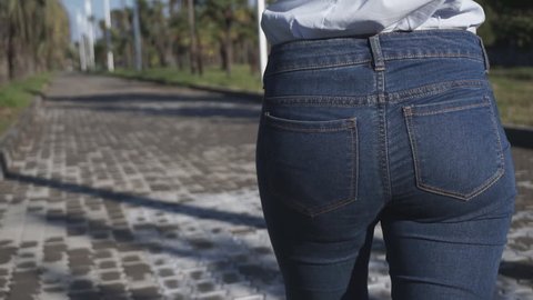 Concept: business, shopping, savings, money. Attractive girl puts back in the jeans pocket stack of dollar bills. Slow motion 60fps. HD