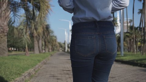 Concept: business, shopping, savings, money. Attractive girl pulls and puts back in the jeans pocket stack of dollar bills. Slow motion 60fps. HD