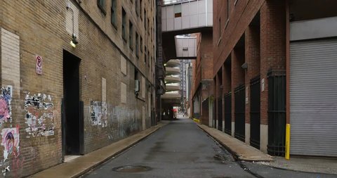 A daytime overcast establishing shot of an empty alley in a big city.  Use as an abandoned, shelter-in-place, quarantine, social distancing concept. Perhaps during a pandemic COVID-19/Coronavirus.
