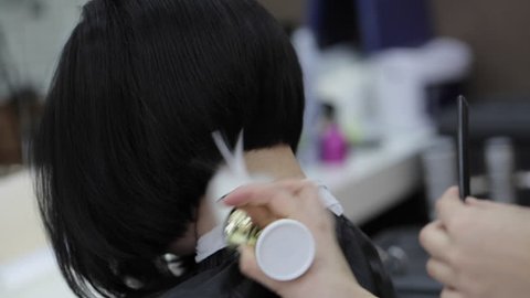 Hairdresser cutting female client's hair in salon and using talc closeup.