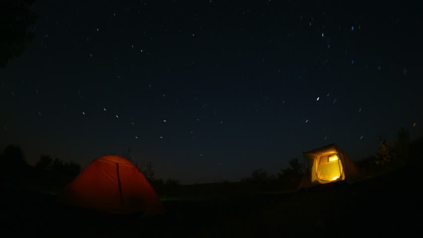 Star trails in the night sky above the tourist tent. Time-lapse.