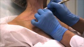 Doctor dermatologist marks points on skin in the neck where she will do beauty treatment