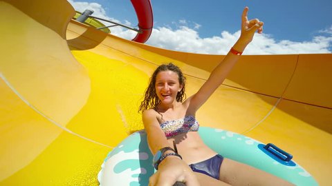 Girl goes down the waterslide tube at aqua park smiling and having fun