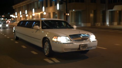 stretched limo driving urban city streets night