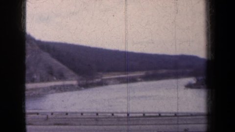 NEW YORK 1959: panorama of a road with cars, a steep lapidarian slope adjacent, and a body of water; parking lot