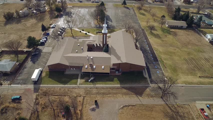 aerial of a church-type building with entrance and parking and adjacent houses